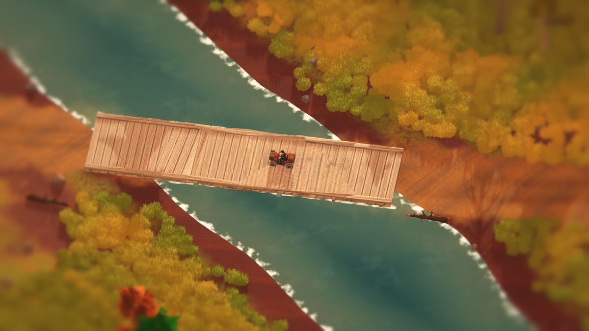 A rider on a red quad bike crosses a wooden plank bridge over a teal river, golden autumn grass and long shadows on both banks.